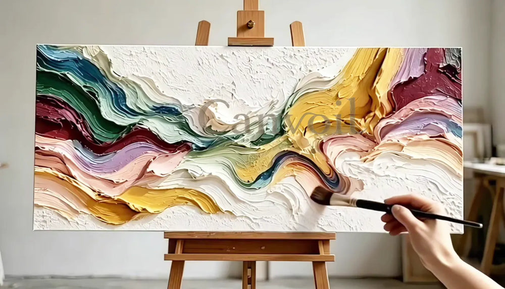 A hand adding a finishing brushstroke to a colorful textured painting on an easel.