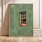 Framed sage green window artwork leaning against a paneled wall on a wood floor.