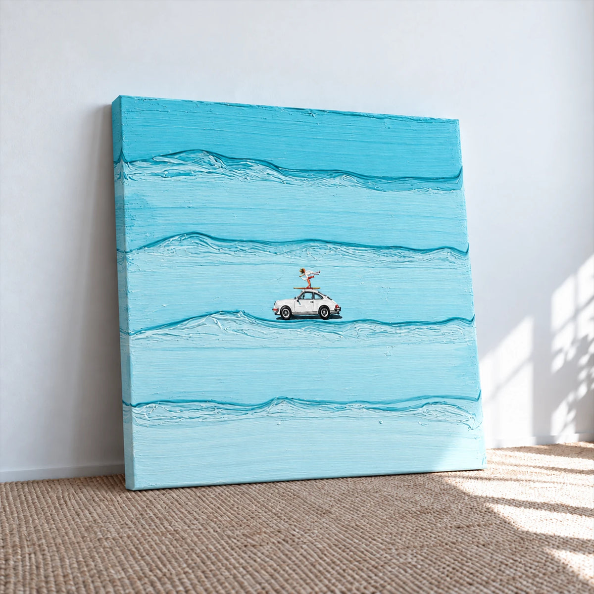 Unframed blue car and surfer canvas leaning against a sunlit wall on a woven rug.