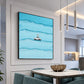 Black-framed blue car and surfer artwork beside a marble dining table and green upholstered chairs.