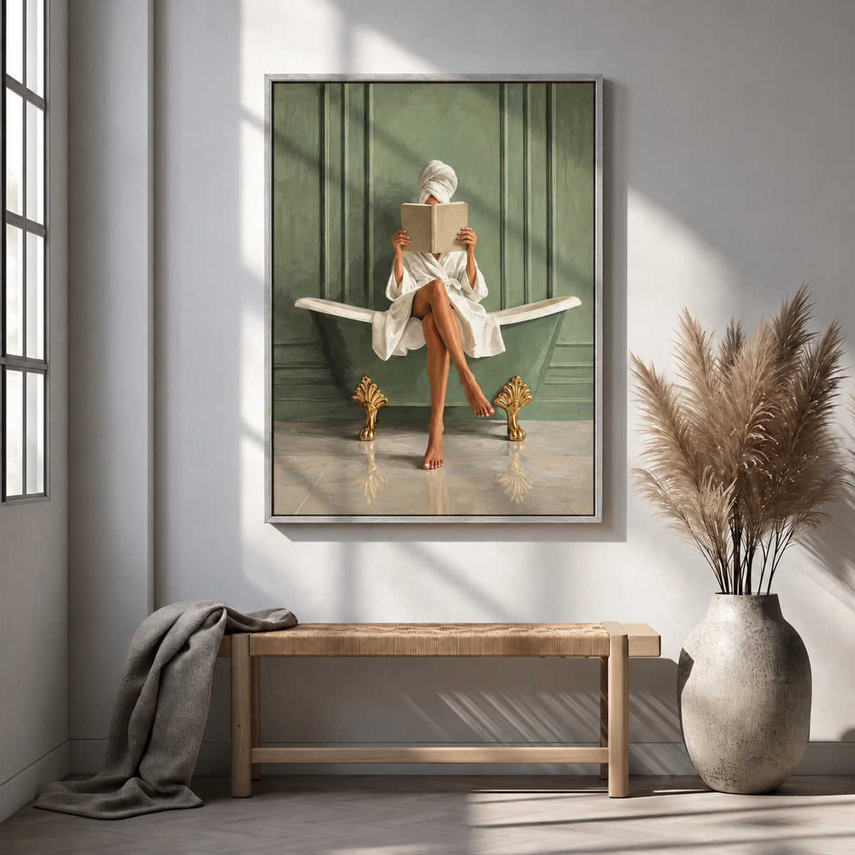Bath reader painting in a silver-gray frame above a woven bench beside a vase of dried grasses.