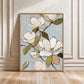 Gold-framed magnolia painting leaning against decorative wall panels on a wood floor.
