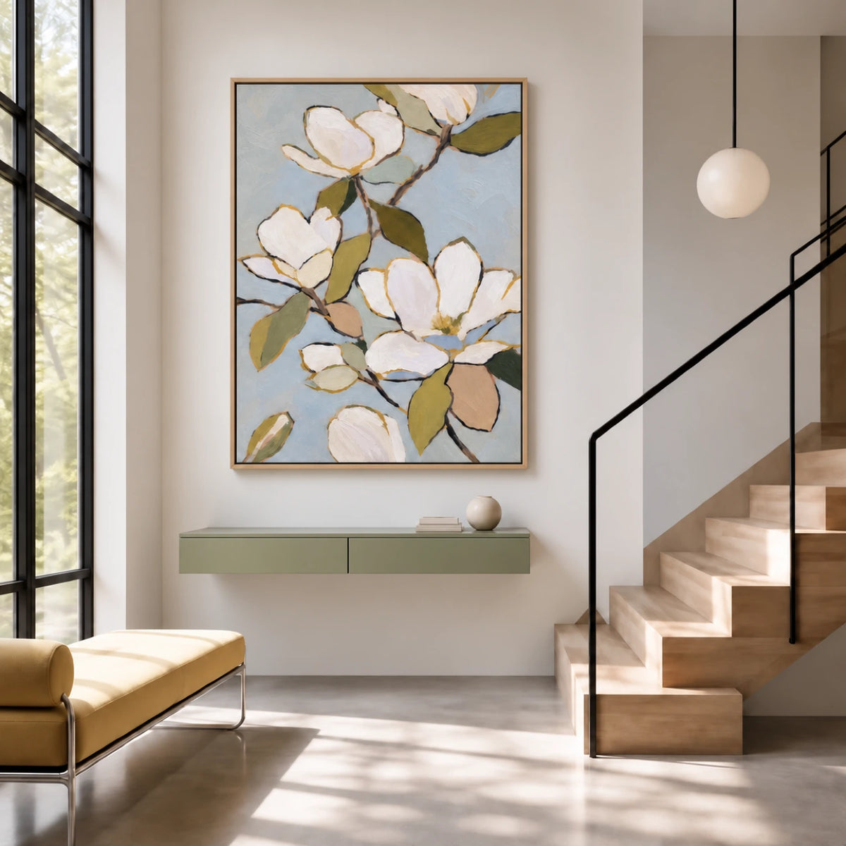 Magnolia wall art above a sage console beside a sunlit staircase.