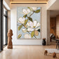 Magnolia painting in a light-colored frame in an airy living space with sculptural decor.