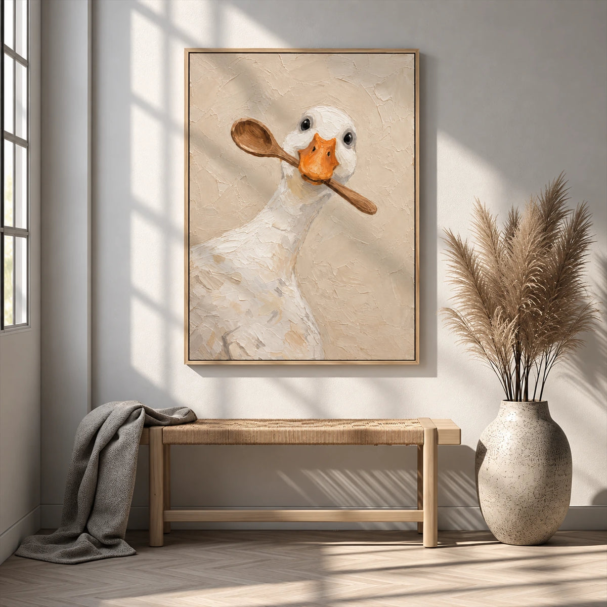 Spoon duck painting above a wood bench beside a large vase of dried grasses in a sunlit room.