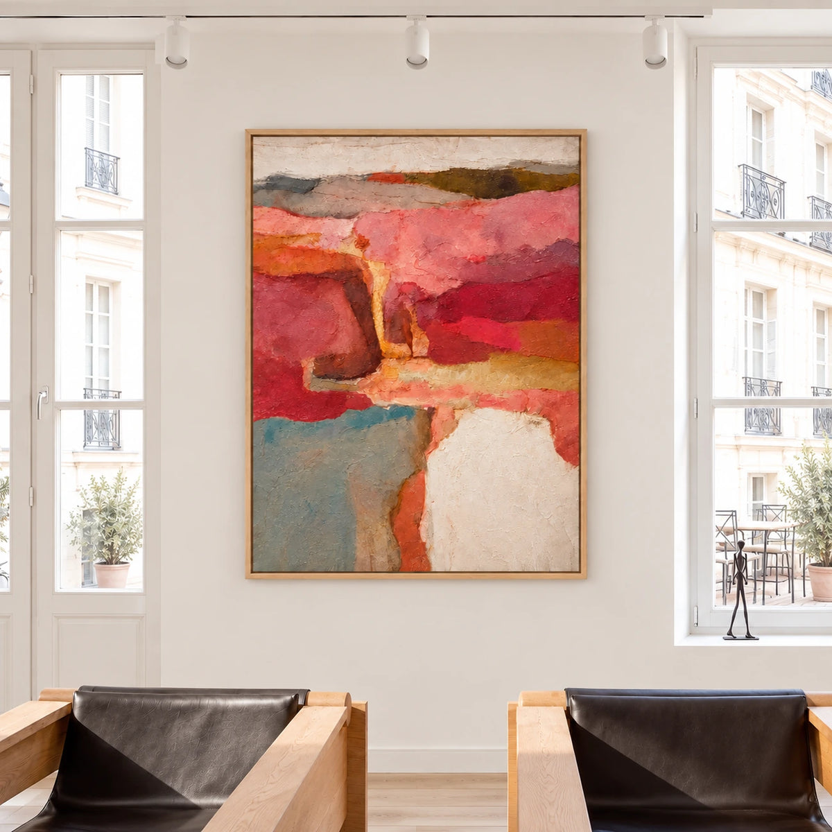 Warm abstract painting displayed between tall windows above two dark lounge chairs.