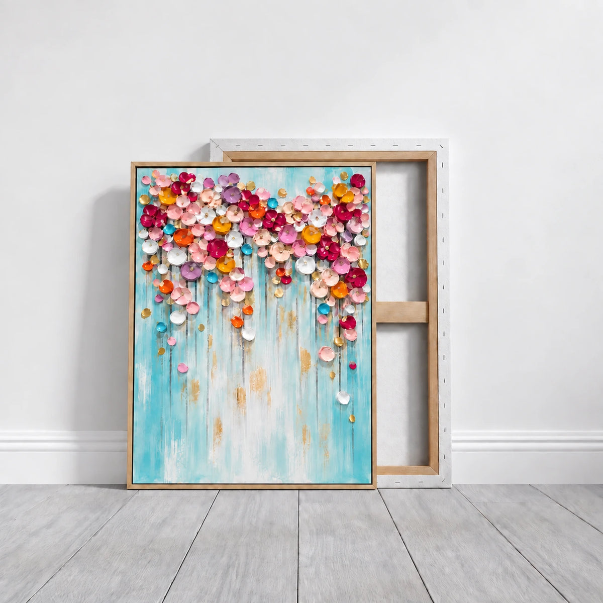 Bloom Cascade painting in a slim gold frame leaning on a pale floor in front of a reverse-facing canvas.