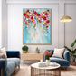 Cascading bloom painting above a living room seating area with blue sofas and a round coffee table.
