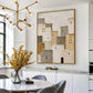 Quiet Village painting in a gold frame above a white dining area with a gold chandelier and yellow branches.