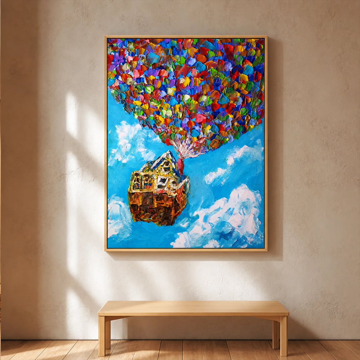 Balloon House painting in a light frame above a simple wood bench on a sunlit wall.
