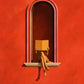 Full artwork of a woman reading a golden book in an arched window against a vivid scarlet wall.