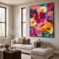 Vivid Blooms painting in a dark frame above a light sectional sofa beside tall windows.