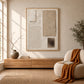 Quiet Forms painting above a low wood cabinet beside a cream armchair with an ochre throw.