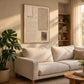 Quiet Forms painting above a cream sofa beside a leafy plant and open shelves.