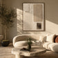 Quiet Forms painting in a dark frame above a curved cream sofa and a rustic stone coffee table.