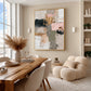 Blush Mosaic painting beside a wood dining table and cream lounge chair near tall windows.