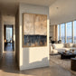 Weathered Calm painting on a dividing wall beside a sunlit living room with tall windows.