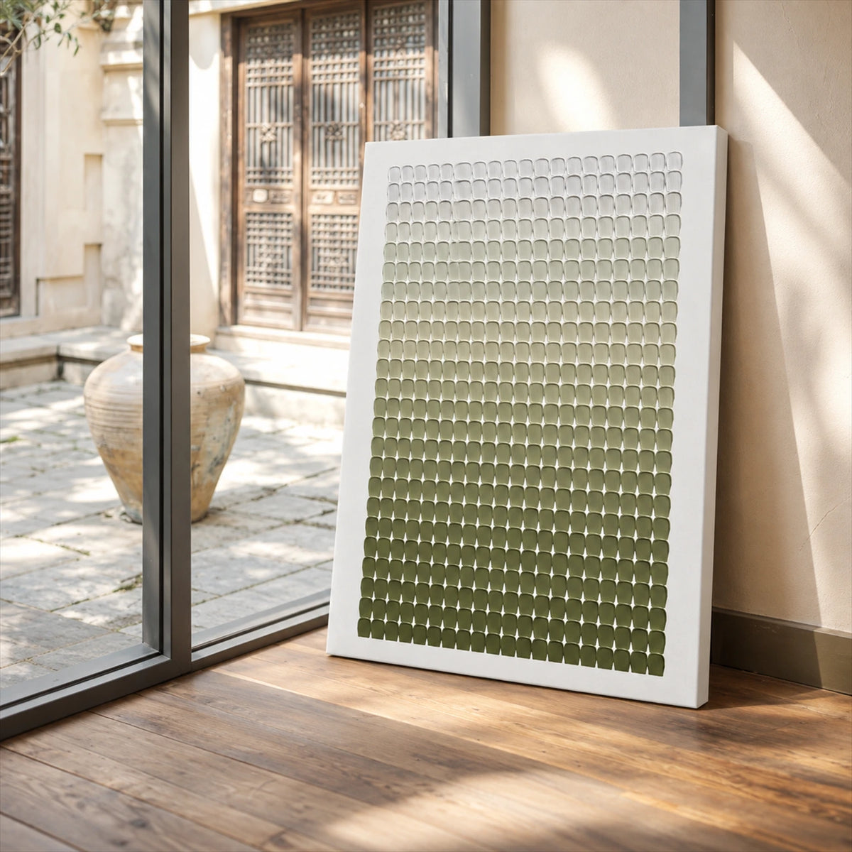 Olive Rhythm canvas leaning against a wall beside glass doors and a sunlit courtyard.