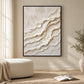 Ivory Tides painting in a black frame beside a cream seat and an open book in a sunlit room.