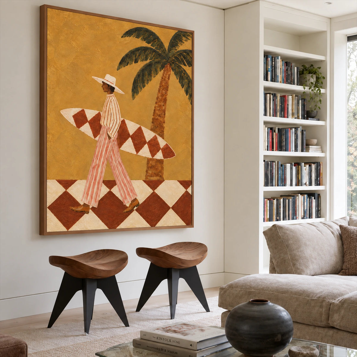 Ochre Surfer painting above two sculptural wooden stools beside bookshelves in a light living room.