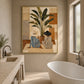 Leafside Companions painting beside a freestanding white bathtub and stone vanity in a bright neutral bathroom.