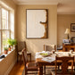 Quiet Perch painting above a wooden dining table in a sunlit room with plants on the windowsill.