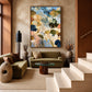 Meadow Reverie painting above olive seating in a tall warm-toned interior beside a staircase.