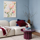 Blush Petals painting above a pale sofa with burgundy accents and a round purple side table against a blue wall.