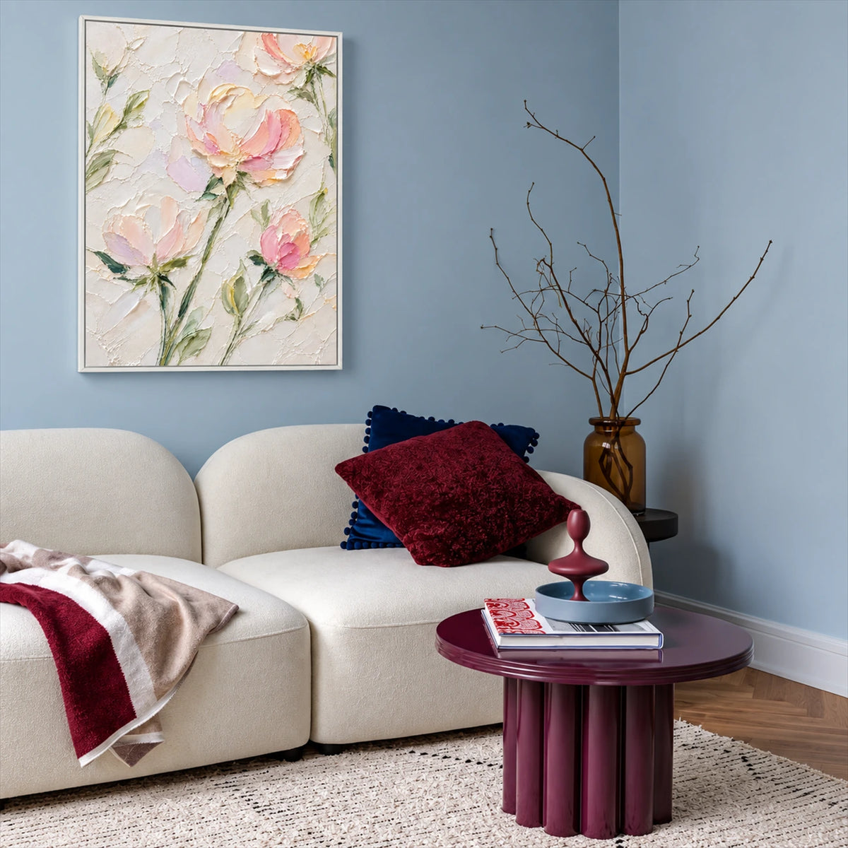 Blush Petals painting above a pale sofa with burgundy accents and a round purple side table against a blue wall.
