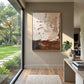 Earthen Layers painting beside a large garden-facing window and pale console in a bright entryway.