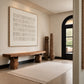Quiet Grid painting above a rustic wooden bench near a black arched doorway in a neutral entryway.