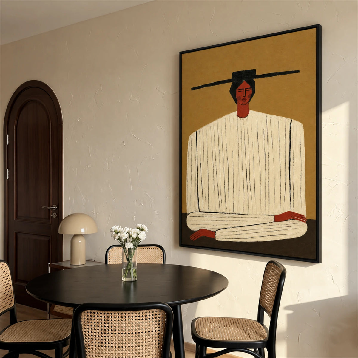 Ochre Stillness painting beside a round black dining table and woven chairs near an arched door.