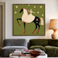 Starlit Rider painting above a two-tone sofa and round wooden coffee table.
