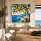 Lemon Coast painting above a wooden dining table beside sea-facing windows.