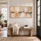 Sandstone Reflection painting above a wooden entry bench with neutral textiles.