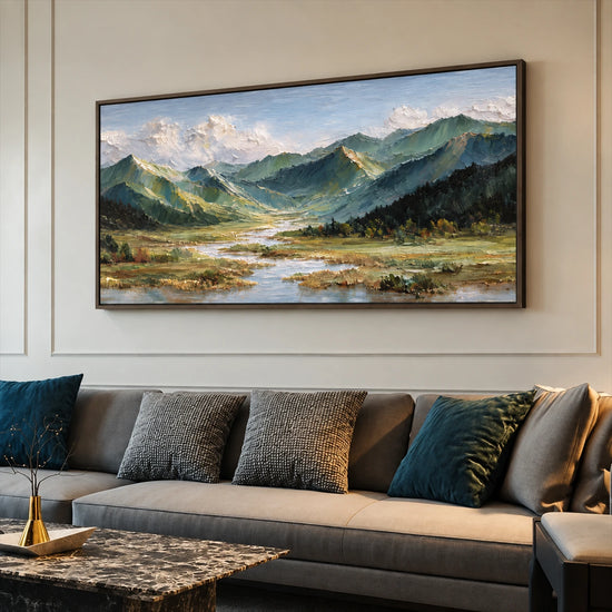 Alpine Waterways painting above a dark gray sofa with colorful cushions.
