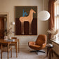Copper Horseman painting above a desk beside a tan leather chair.