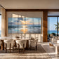 Sunset Shore painting above a dining table beside ocean-facing windows.