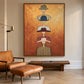 Hat Parade artwork displayed above a low wooden console beside a brown leather lounge chair.