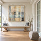 Pebble Grid artwork displayed above a long wooden bench beside tall windows and decorative vases.