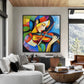 Chromatic Strings artwork displayed above a console beside gray seating and tall windows.