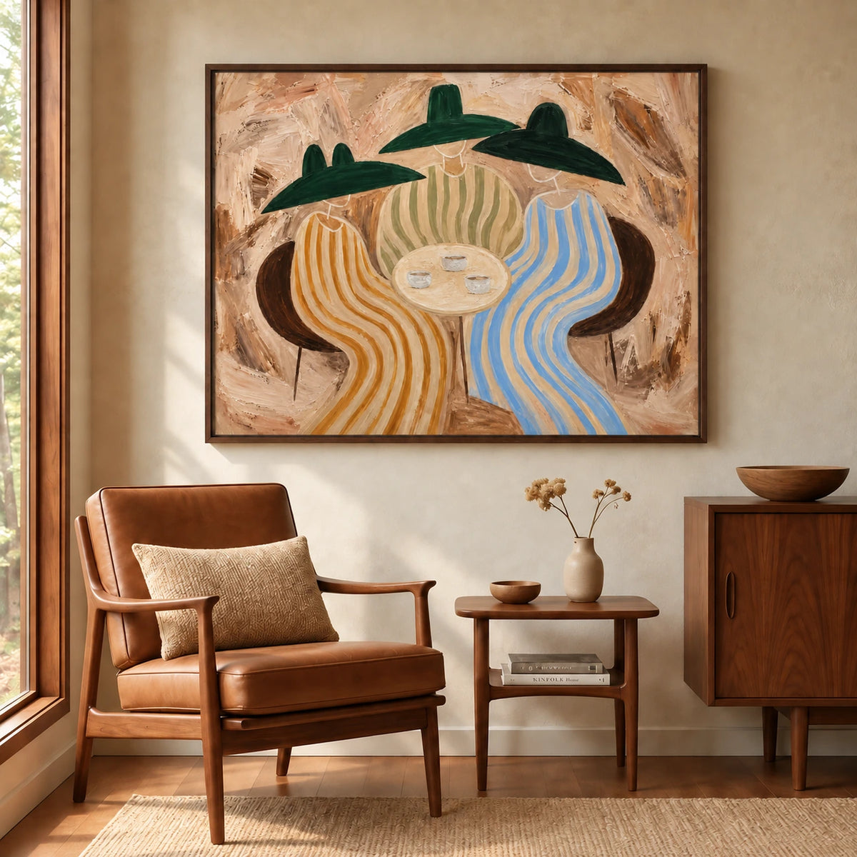 Striped Gathering artwork displayed above a leather armchair and side table beside a window.