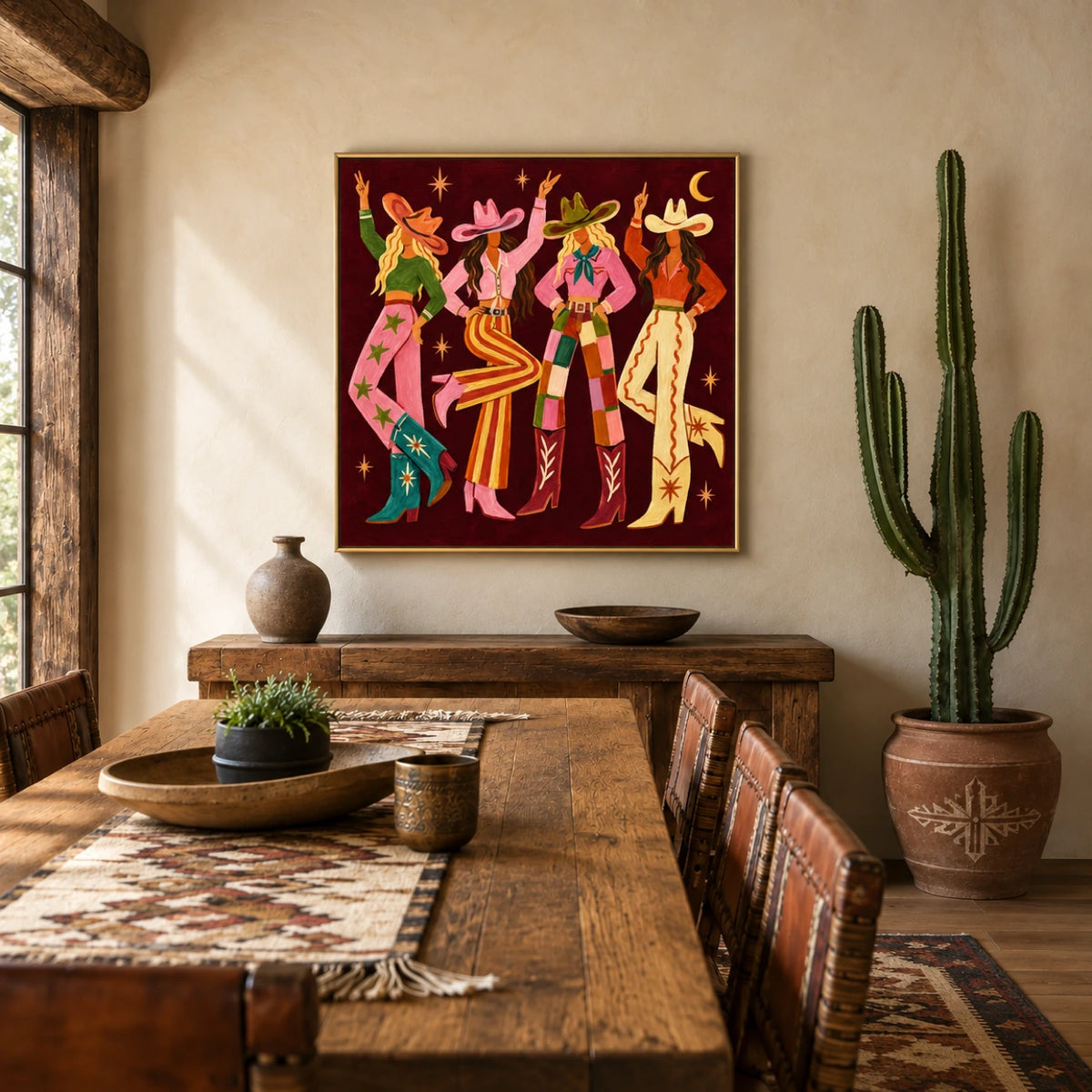 Cowgirl Revelry artwork displayed above a wooden console behind a rustic dining table.