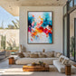 Chromatic Flourish artwork displayed above a cream sectional beside a garden.