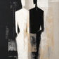 Divided Silhouette full artwork. An elongated figure stands between contrasting fields of ivory and black, its angular silhouette shifting between light and shadow.