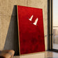 Crimson Flight Wall Art in a slim gold frame leaning against a textured stone wall beside a tall window.