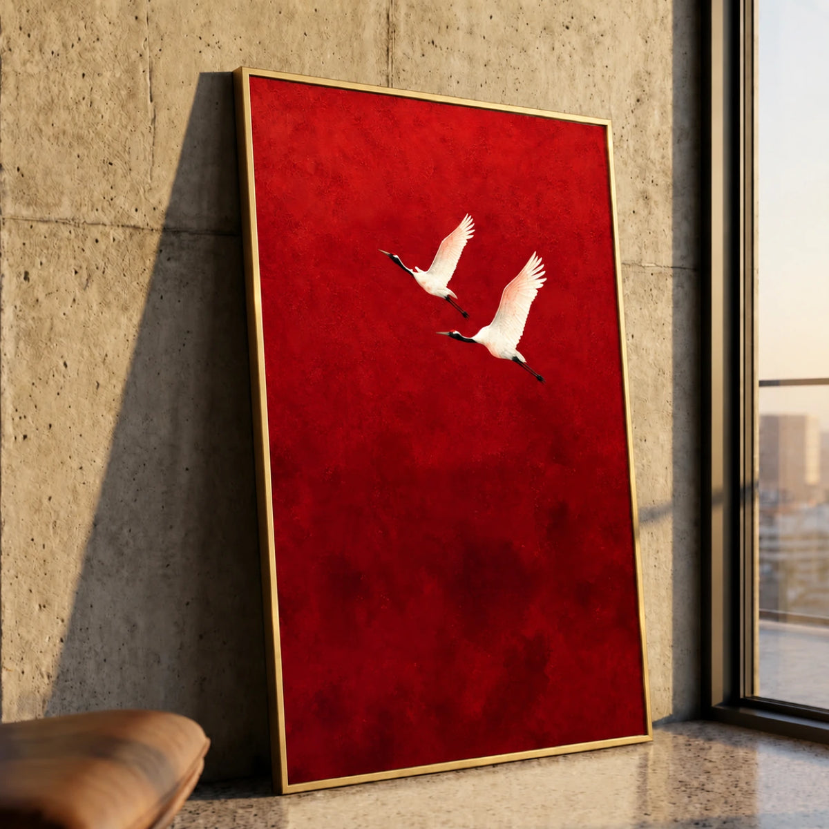 Crimson Flight Wall Art in a slim gold frame leaning against a textured stone wall beside a tall window.
