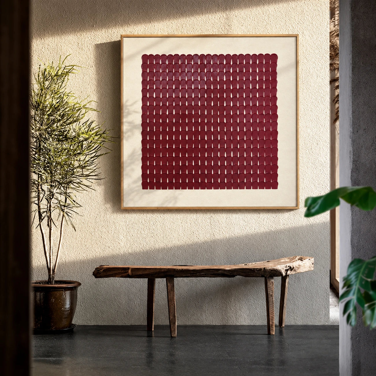 Burgundy Rhythm artwork displayed above a wooden bench beside an indoor tree.