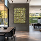Olive Tessera artwork displayed above a dining table beside garden windows.