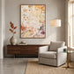 Amber Traces artwork displayed above a wooden sideboard beside a pale armchair.